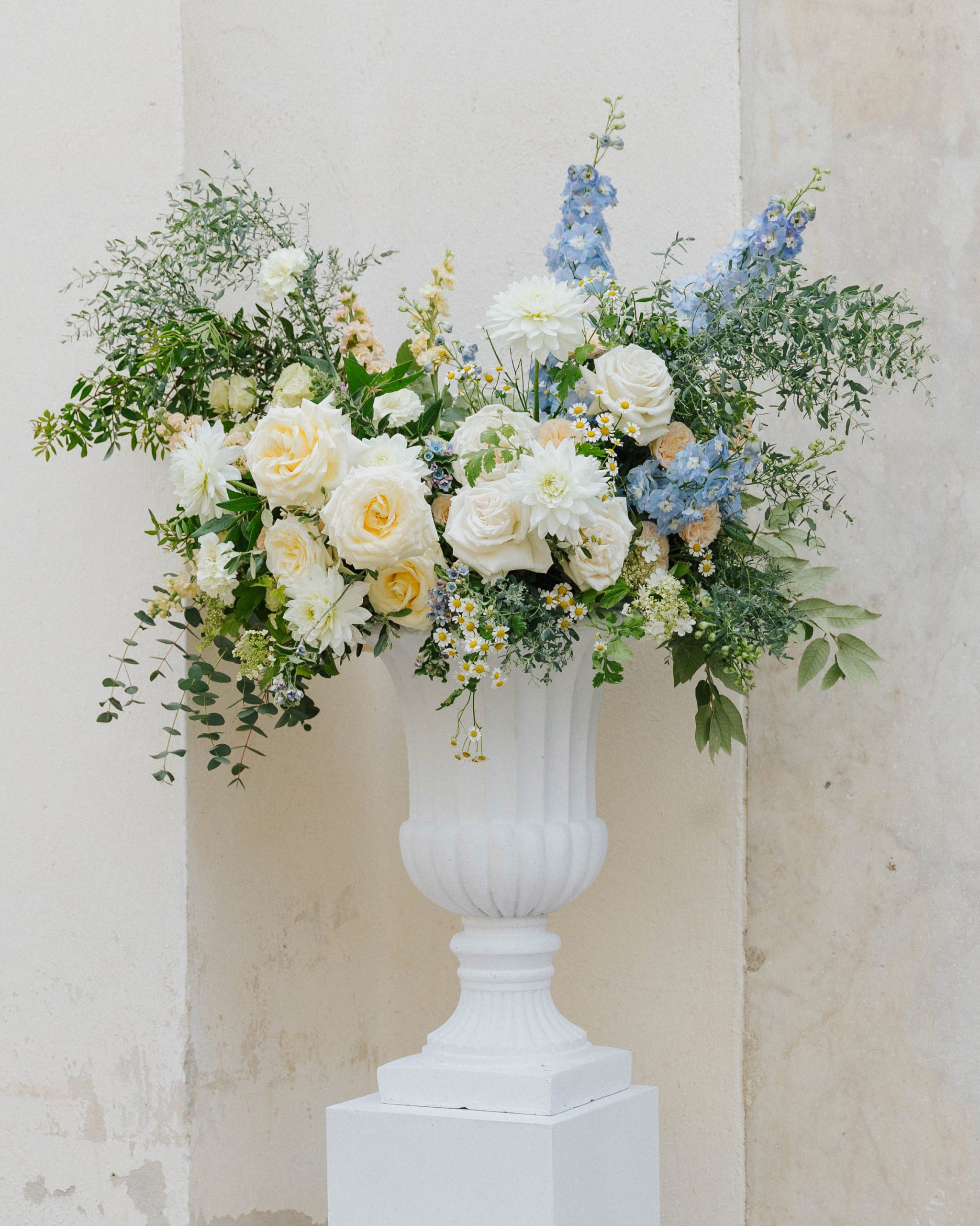 White vase with yellow, white and dusty blue flower arrangement