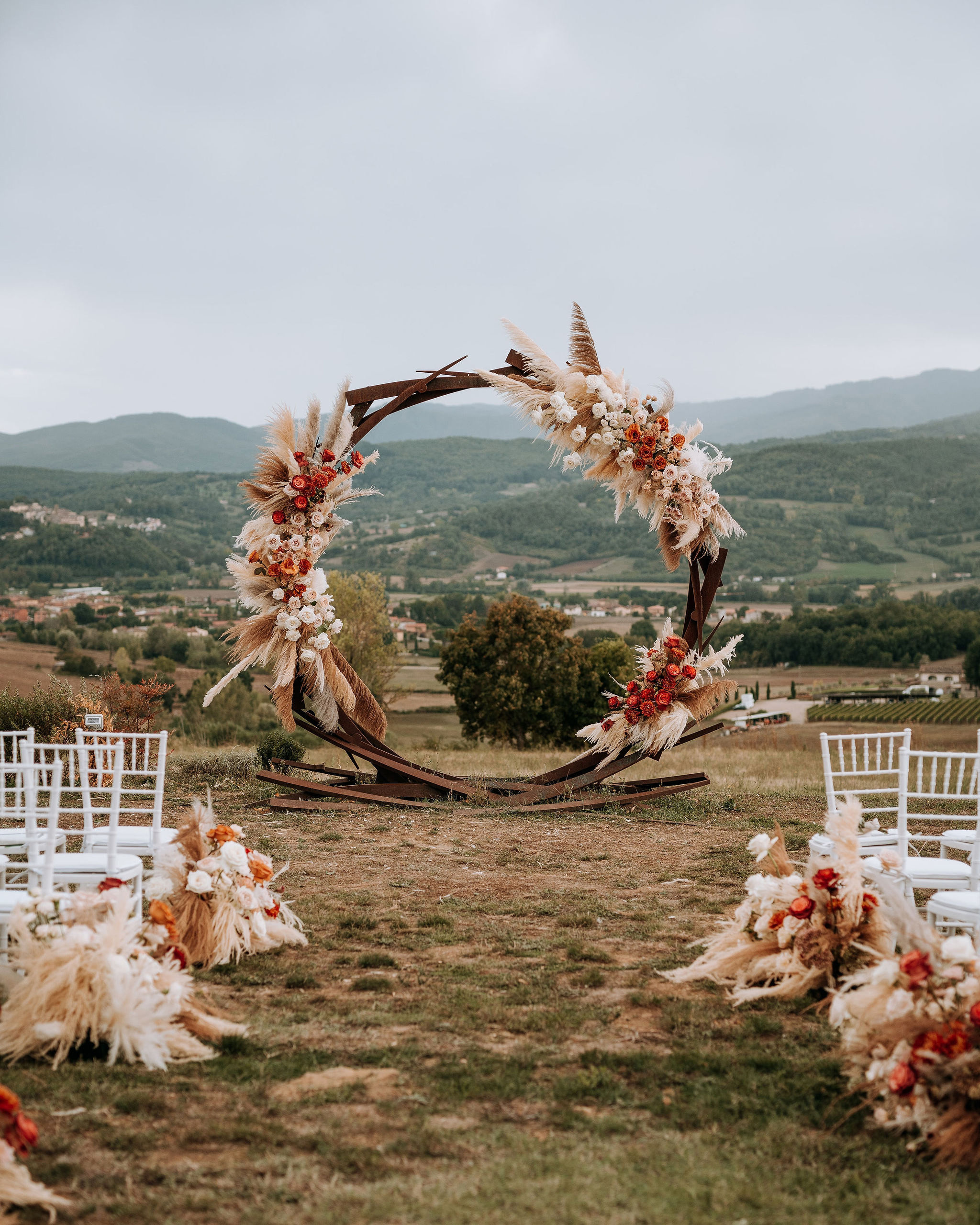 Iron wedding arch decorated with pampas grass and roses in neutral tones